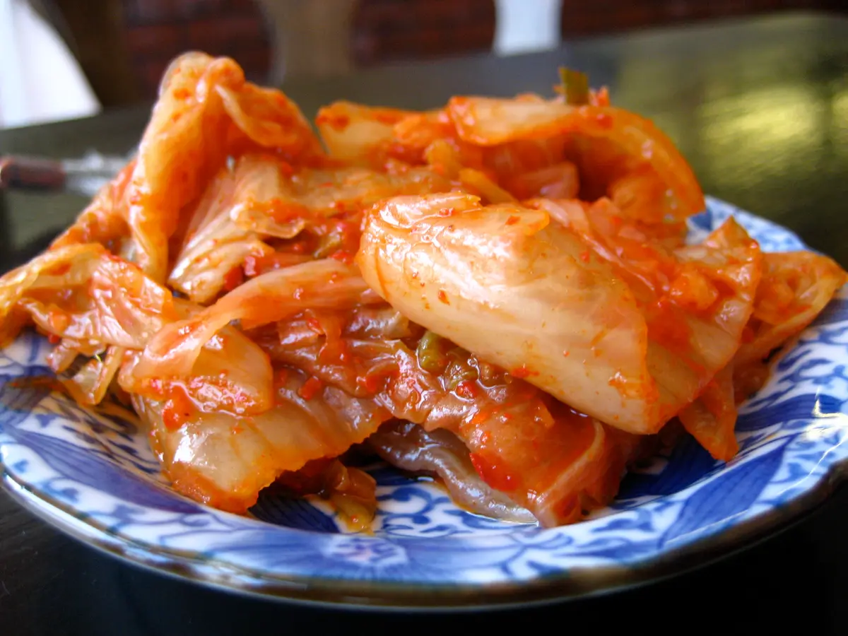 A plate of red napa cabbage kimchi on a blue and white patterned dish