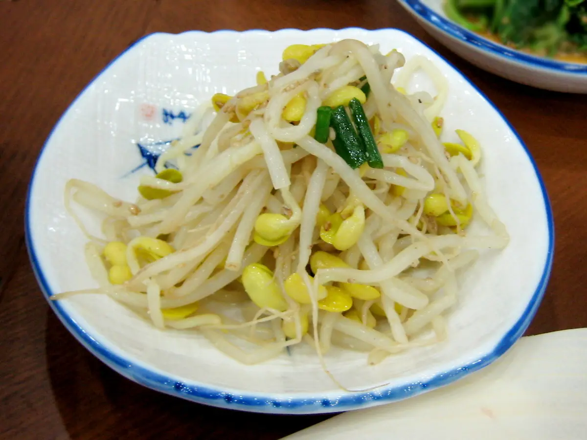 Kongnamul muchim, seasoned soybean sprouts with green onion on a white and blue plate